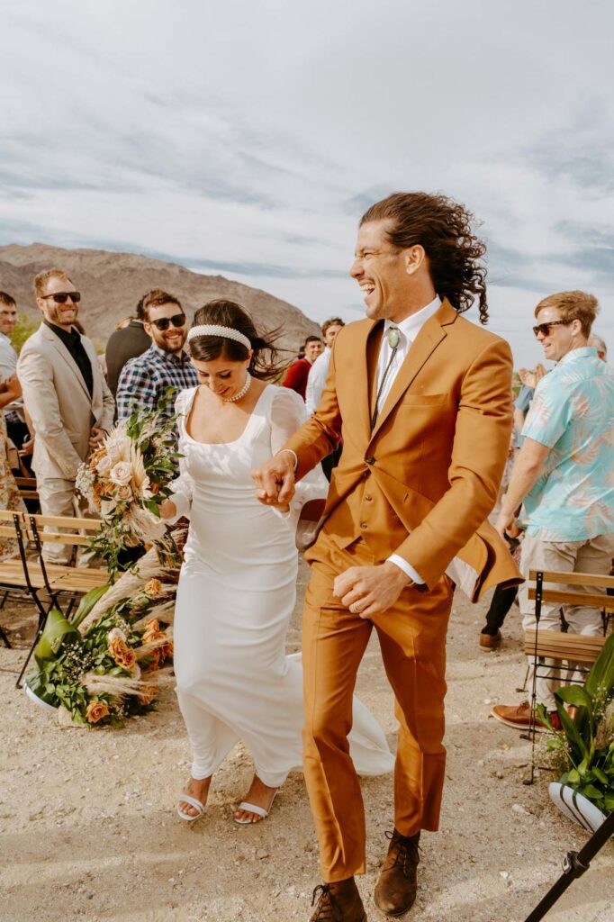 Happy groom smiling as he walks down aisle with his new wife  — Desert Wedding Photography by Mattie O'Neill